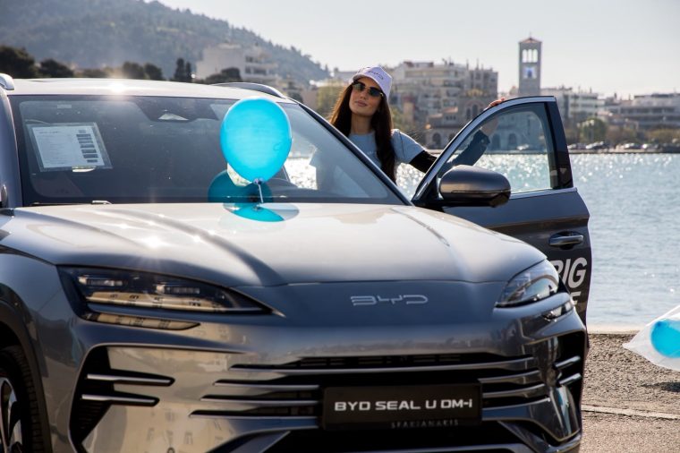 Υπαίθρια ενέργεια BYD δίπλα στη θάλασσα, με branded διακόσμηση.